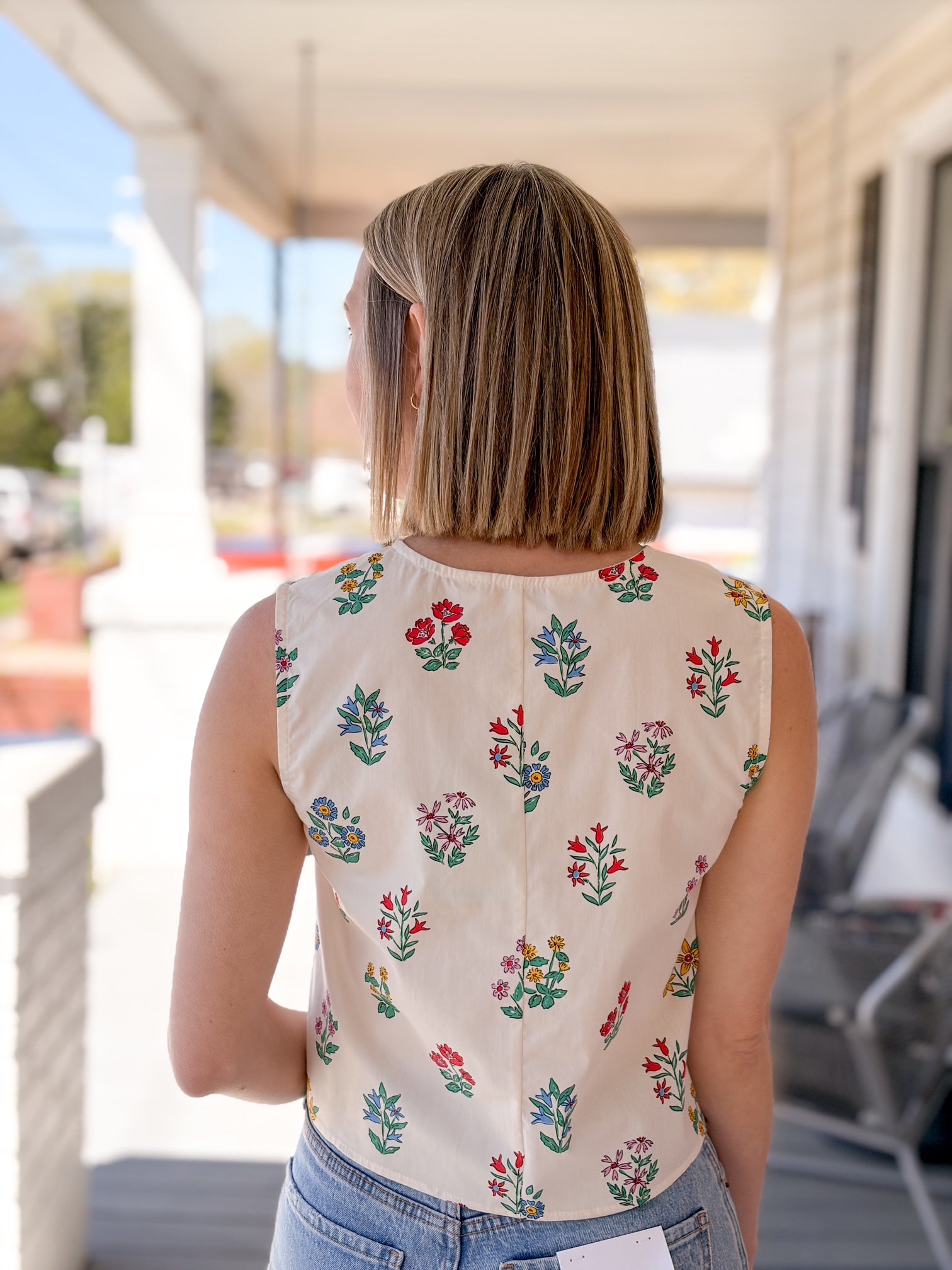 cream sleeveless top with floral pattern, button up front